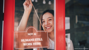 Woman hanging “Humans Still Work Here” sign in storefront